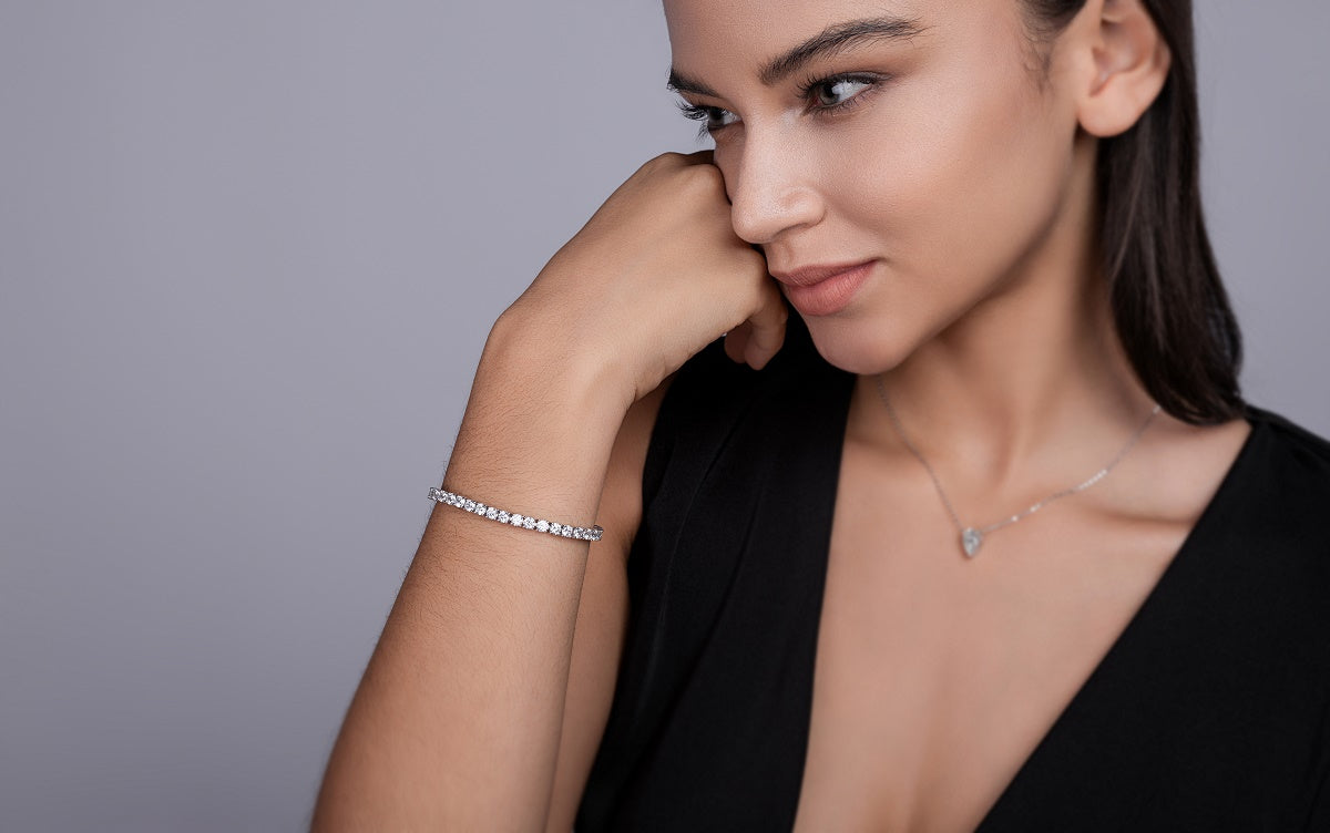 Woman wearing a bracelet and necklace against a gray background